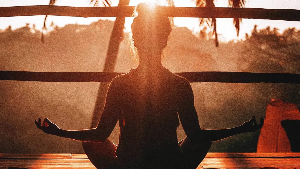 A woman doing Yoga as the sun rises.