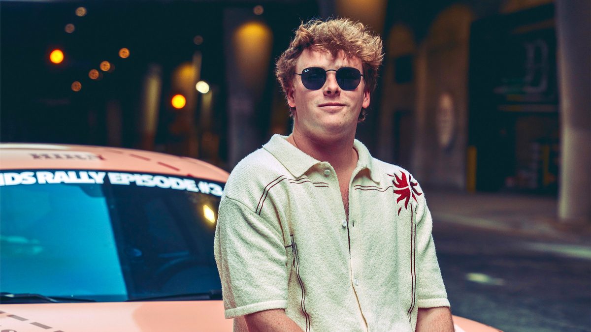 Daniel Mac leaning on an orange car