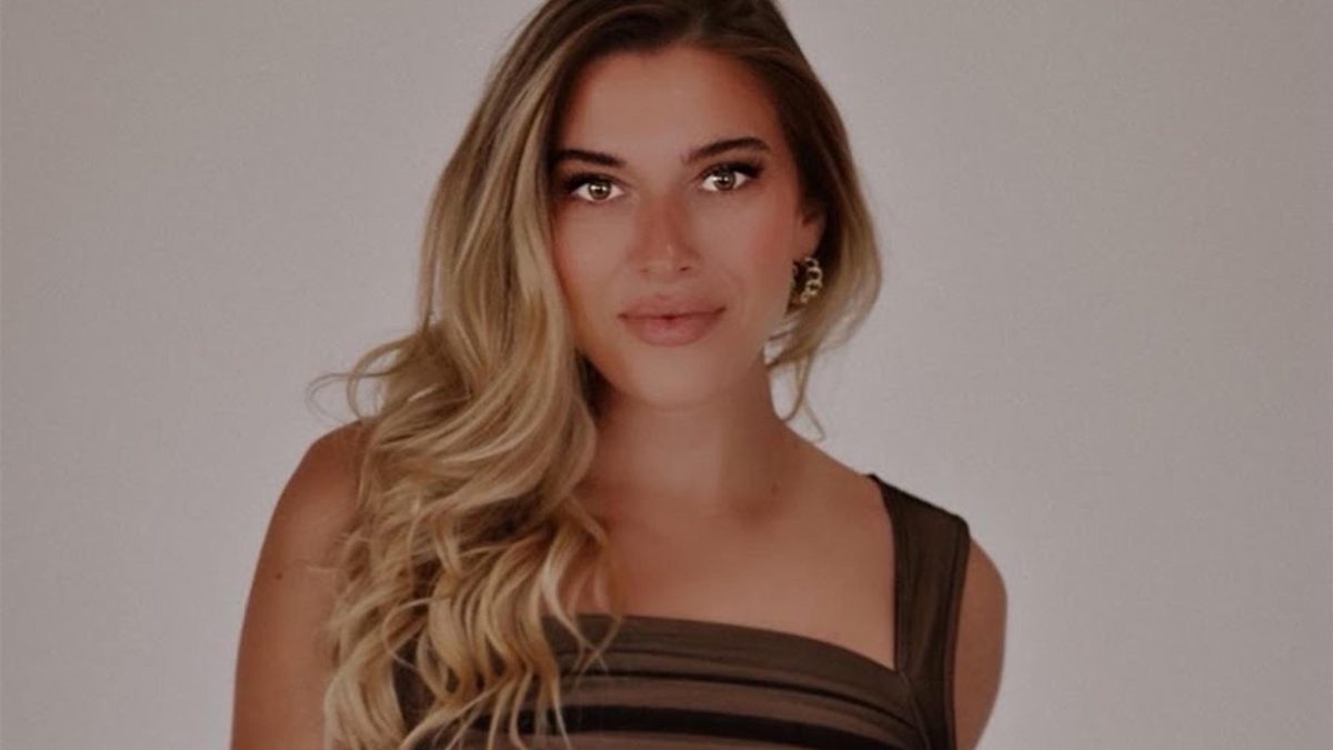 Taylor Mathis in brown dress standing against white wall