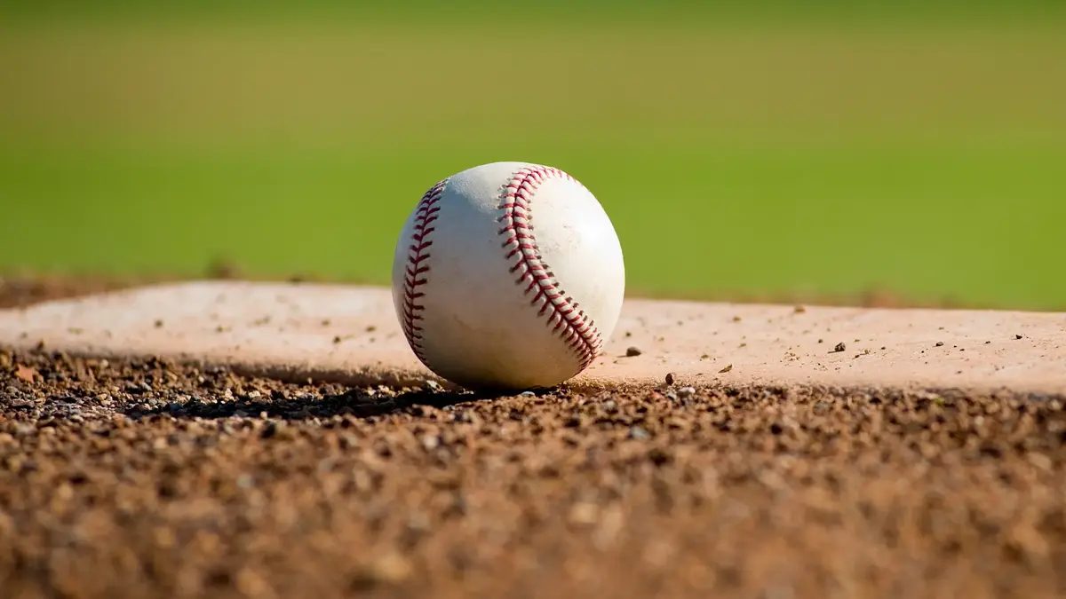 a white leather baseball lying on top of the pitcher's mound at a baseball field with copy space xkwx baseball