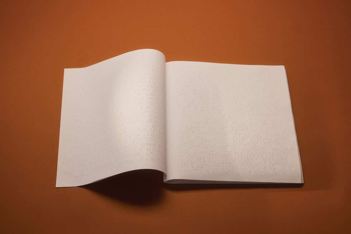 An open braille edition of Playboy against a burnt orange background.